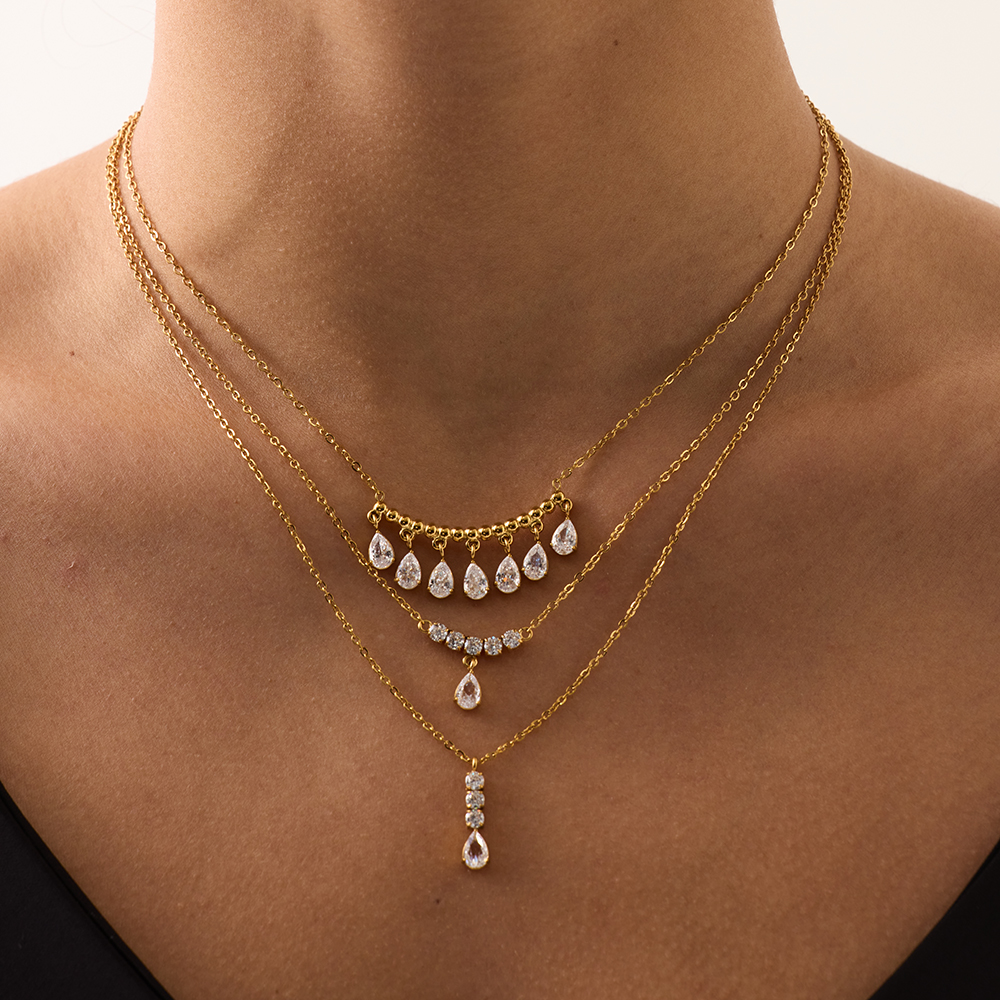 Model wearing layered thin gold chains with zircon accents