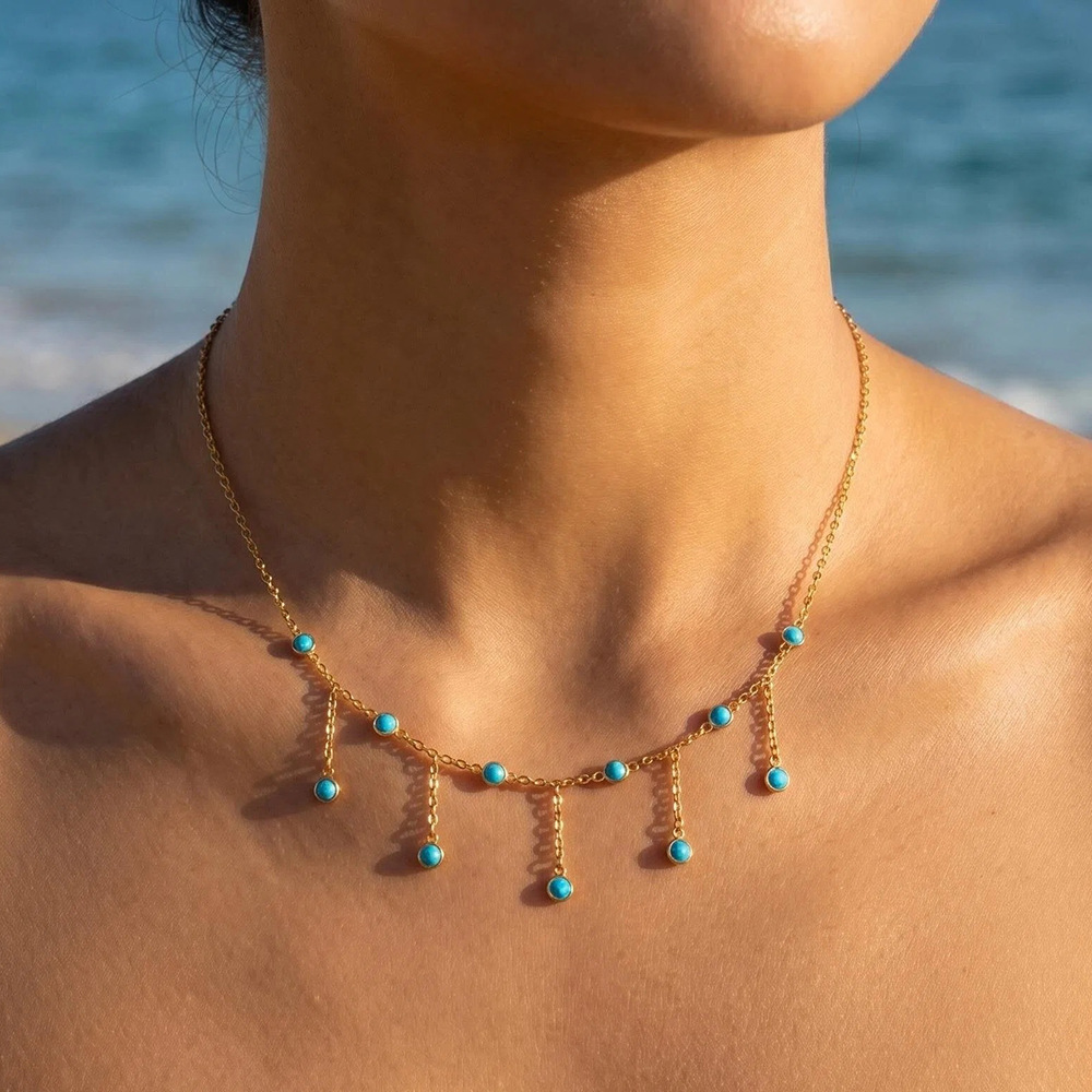 Model wearing a gold necklace with natural turquoise stone tassel drops